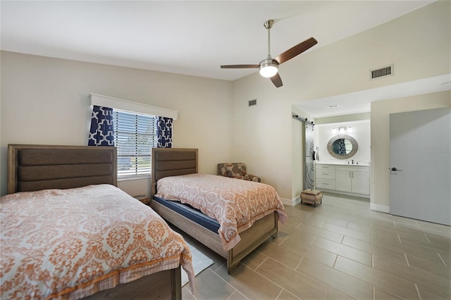 bedroom featuring ensuite bath, vaulted ceiling, ceiling fan, a barn door, and light tile patterned flooring