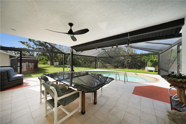 view of swimming pool featuring a lawn, ceiling fan, a patio area, and a storage shed