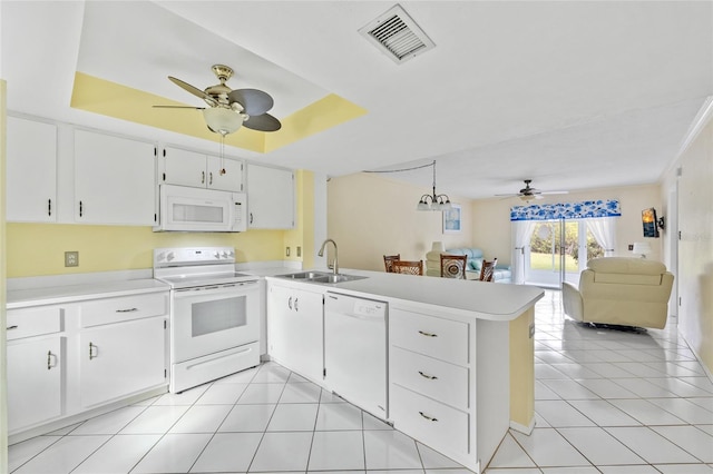 kitchen featuring kitchen peninsula, white appliances, a raised ceiling, and sink