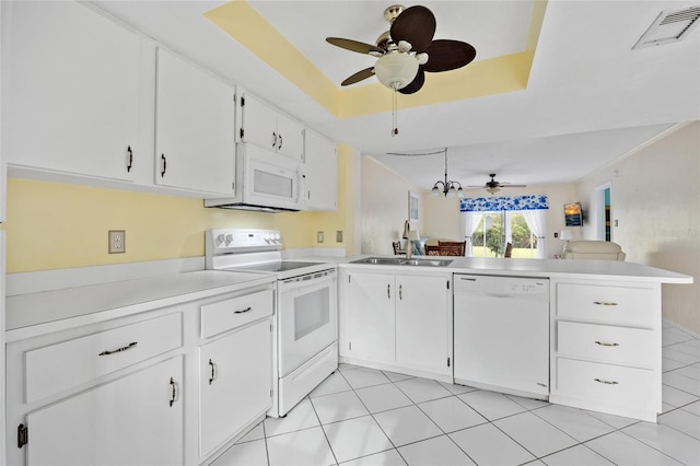 kitchen featuring white appliances, white cabinets, a raised ceiling, sink, and kitchen peninsula