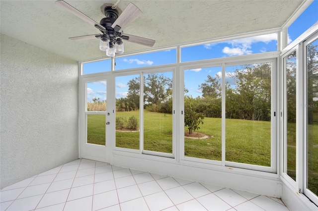 unfurnished sunroom featuring ceiling fan and plenty of natural light