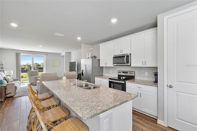 kitchen with a breakfast bar, sink, an island with sink, and appliances with stainless steel finishes