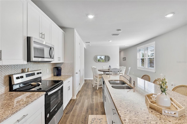 kitchen with light stone countertops, sink, white cabinets, and stainless steel appliances