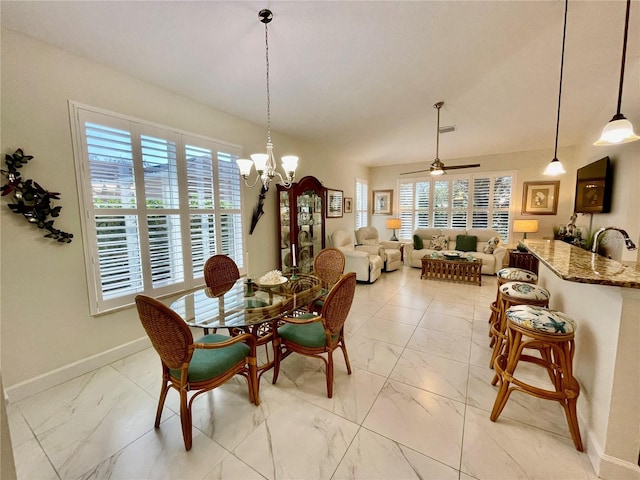 dining room with ceiling fan with notable chandelier, a wealth of natural light, and sink