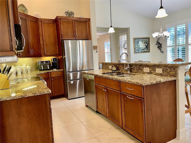 kitchen with sink, an inviting chandelier, tasteful backsplash, pendant lighting, and appliances with stainless steel finishes