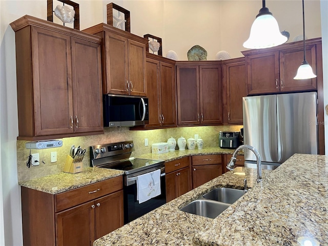 kitchen with decorative backsplash, light stone counters, stainless steel appliances, sink, and decorative light fixtures