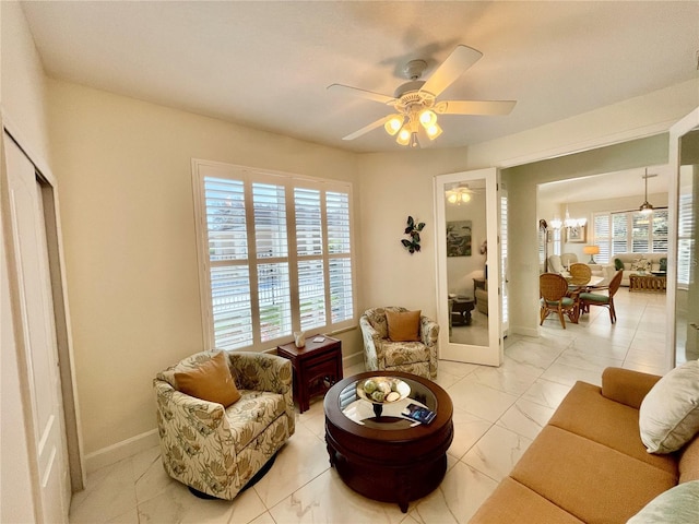 living room with a wealth of natural light, french doors, and ceiling fan with notable chandelier