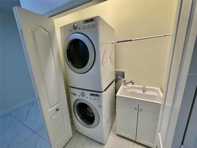 laundry area with stacked washer / drying machine and sink