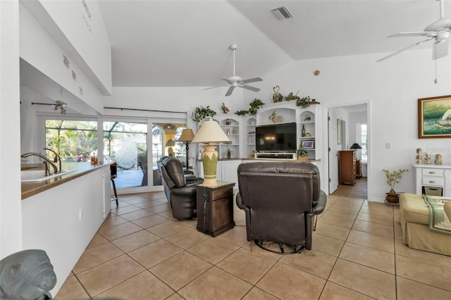 living room featuring sink, light tile patterned floors, and vaulted ceiling