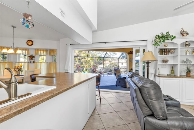 kitchen featuring sink, hanging light fixtures, light tile patterned floors, an inviting chandelier, and white cabinets