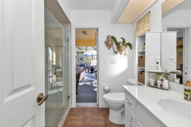 bathroom featuring tile patterned floors, vanity, toilet, and a shower with shower door