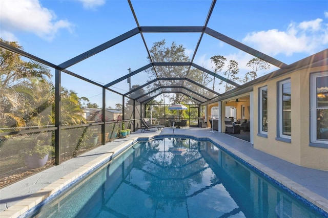 view of swimming pool featuring ceiling fan, a patio area, and glass enclosure