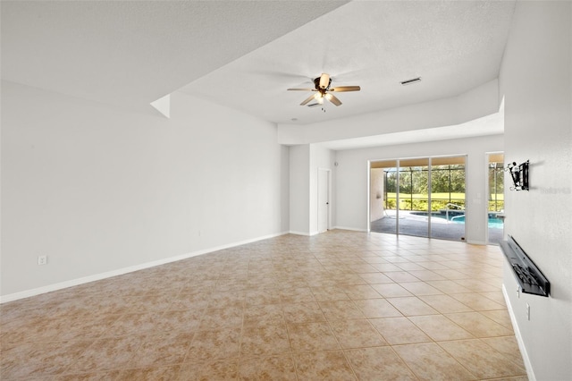 empty room with ceiling fan, light tile patterned floors, and a textured ceiling