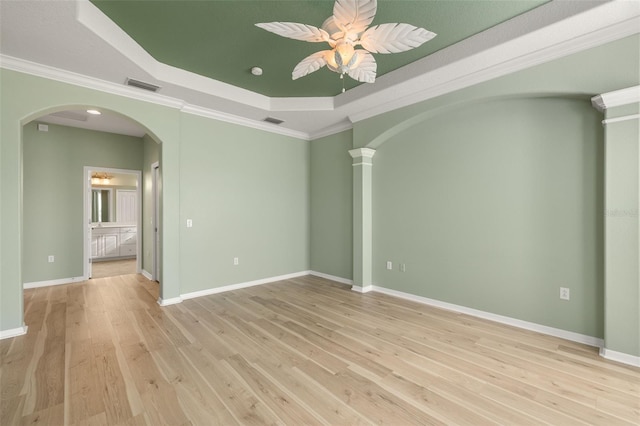 unfurnished room with ceiling fan, a raised ceiling, ornamental molding, and light wood-type flooring