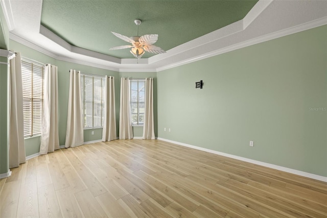 unfurnished room featuring ceiling fan, crown molding, light hardwood / wood-style flooring, and a tray ceiling