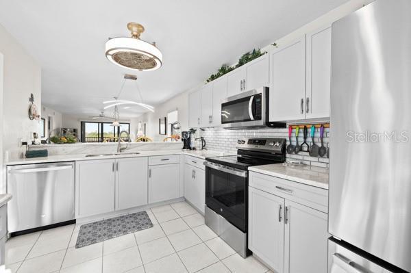 kitchen featuring tasteful backsplash, white cabinetry, sink, kitchen peninsula, and stainless steel appliances