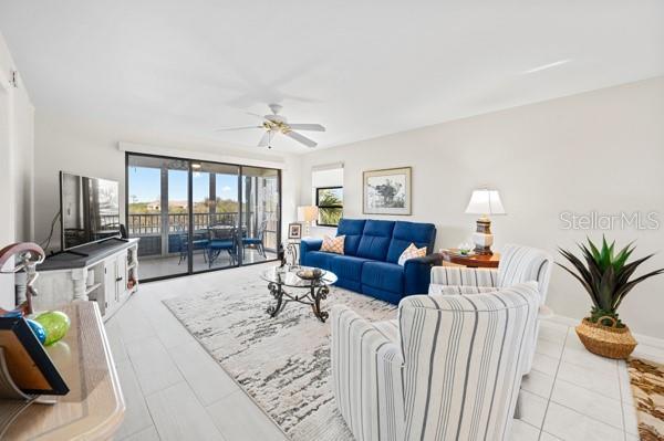 tiled living room with ceiling fan and a wall of windows