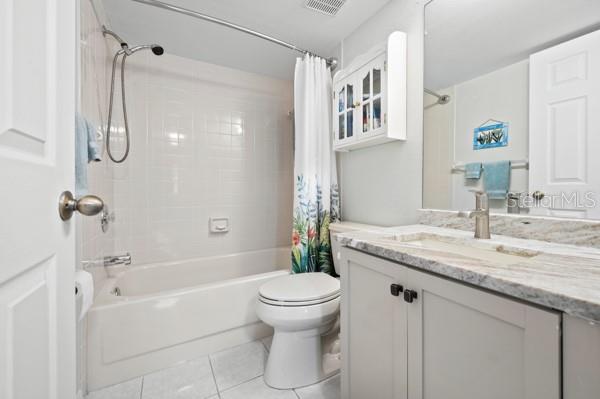 full bathroom featuring vanity, shower / bath combination with curtain, tile patterned floors, and toilet