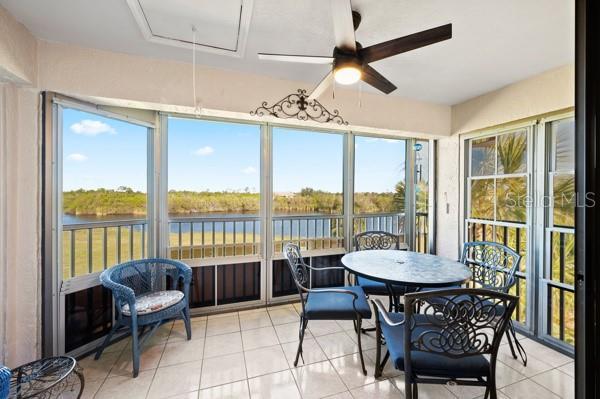 sunroom / solarium featuring a wealth of natural light, ceiling fan, and a water view