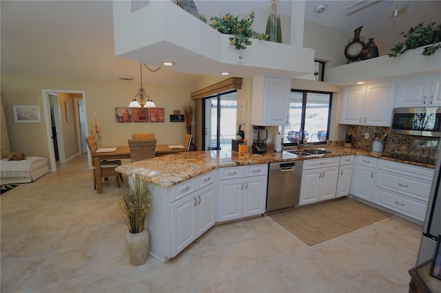 kitchen featuring stone counters, sink, hanging light fixtures, stainless steel appliances, and white cabinets