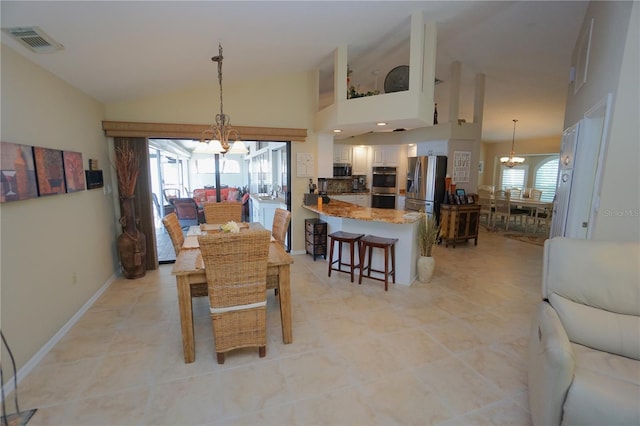 dining room with a wealth of natural light, high vaulted ceiling, light tile patterned floors, and a notable chandelier