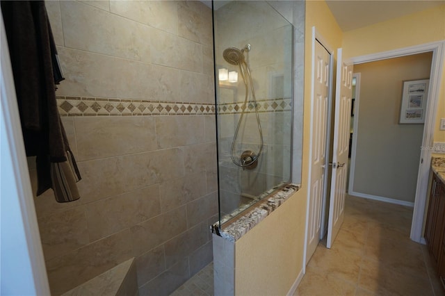 bathroom with tiled shower, vanity, and tile patterned flooring