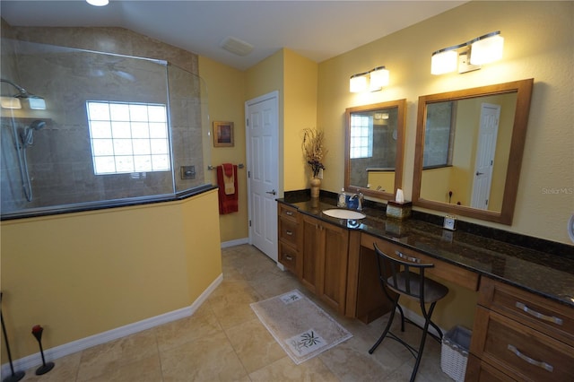 bathroom with tile patterned flooring, vanity, a tile shower, and lofted ceiling