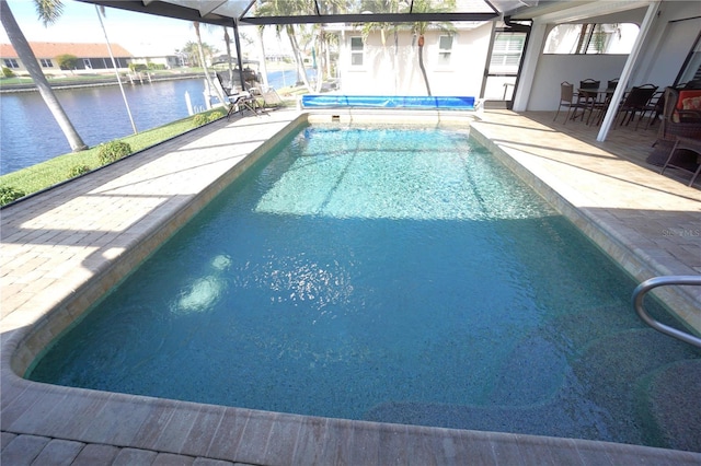 view of swimming pool featuring glass enclosure, a patio area, and a water view