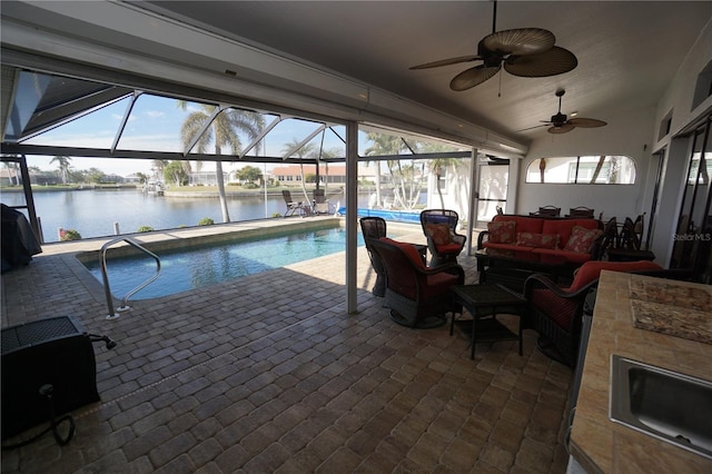 view of pool with outdoor lounge area, a water view, ceiling fan, and sink