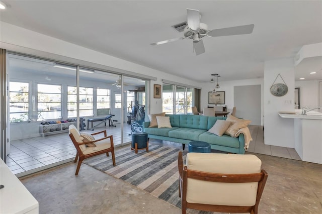 living room featuring concrete flooring, ceiling fan, and a healthy amount of sunlight