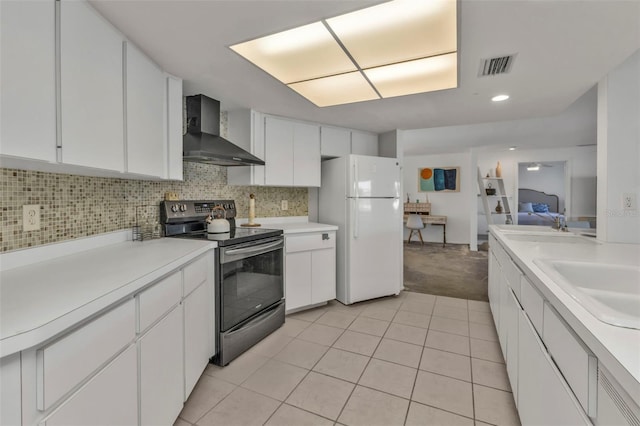 kitchen featuring stainless steel range with electric stovetop, white cabinets, wall chimney range hood, sink, and white fridge