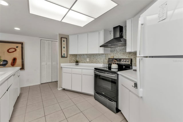 kitchen with electric range, white refrigerator, white cabinets, and wall chimney range hood