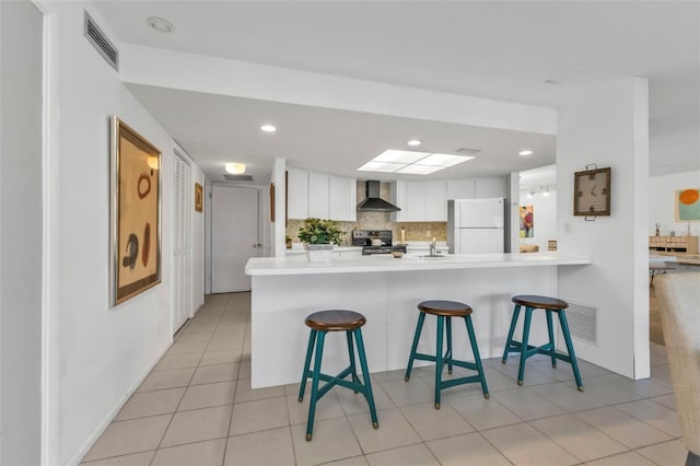 kitchen featuring kitchen peninsula, white cabinetry, stainless steel electric range oven, and white refrigerator