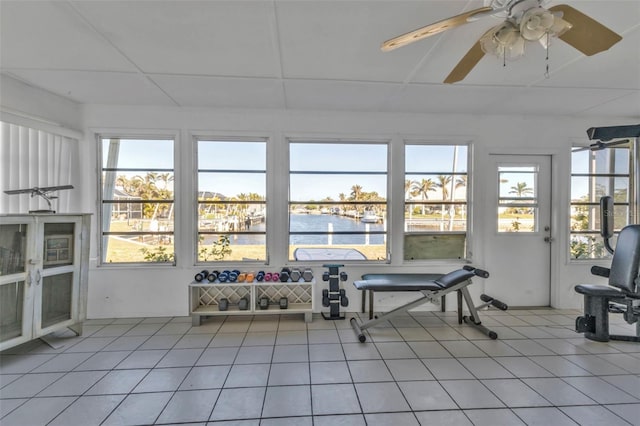 unfurnished sunroom featuring ceiling fan, plenty of natural light, a water view, and a drop ceiling