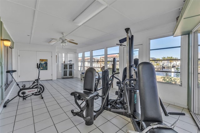 gym featuring light tile patterned floors, a water view, and ceiling fan