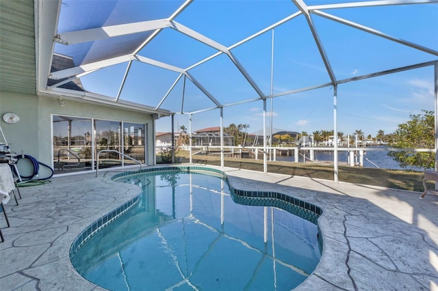 view of pool with glass enclosure, a patio area, and a water view