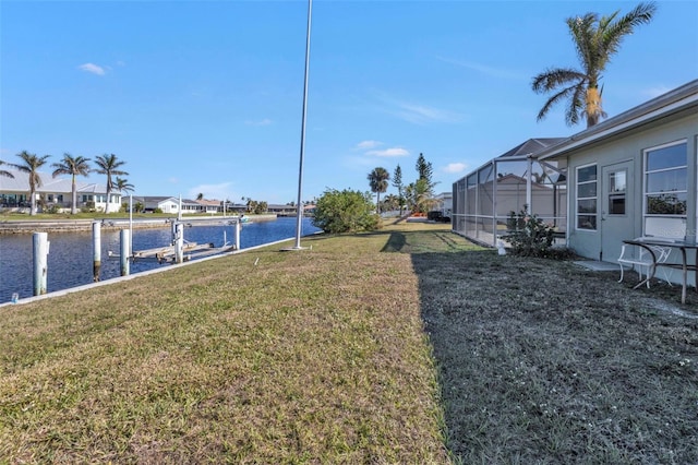 view of yard featuring a lanai, a water view, and a boat dock