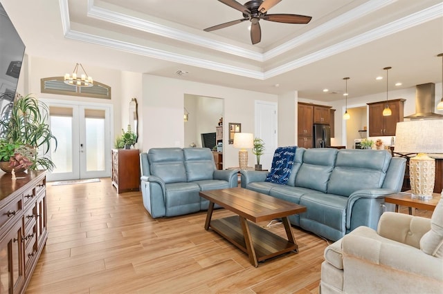 living room with french doors, ornamental molding, a tray ceiling, and light hardwood / wood-style floors