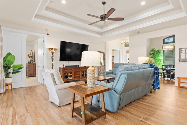 living room with ornamental molding, a raised ceiling, and light hardwood / wood-style flooring