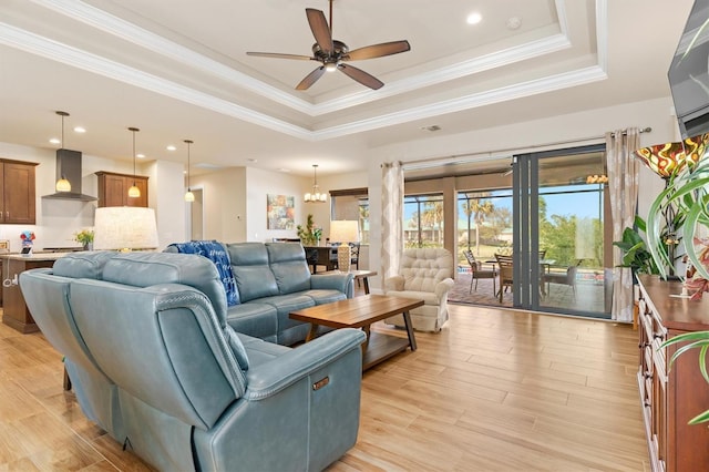 living room with crown molding, a tray ceiling, and light wood-type flooring