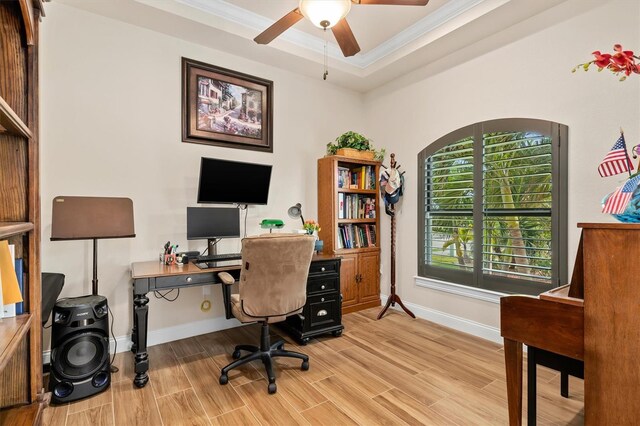 office area featuring ornamental molding, light hardwood / wood-style floors, a raised ceiling, and ceiling fan