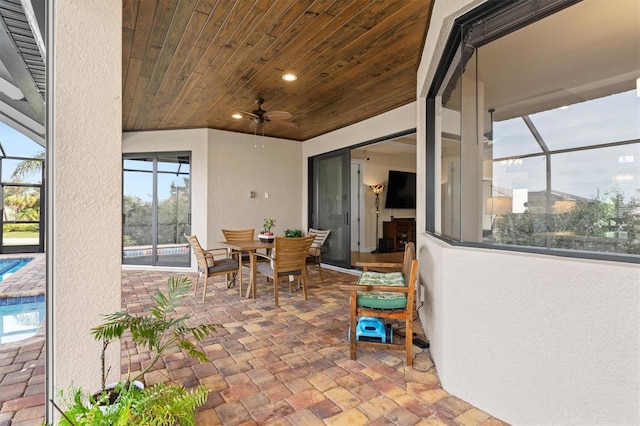 view of patio / terrace featuring ceiling fan and glass enclosure