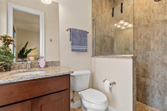 bathroom featuring a tile shower, vanity, and toilet