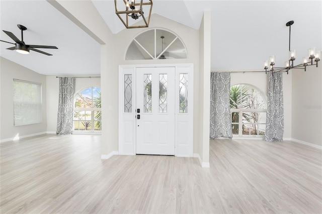 foyer entrance featuring ceiling fan with notable chandelier, light hardwood / wood-style floors, and vaulted ceiling