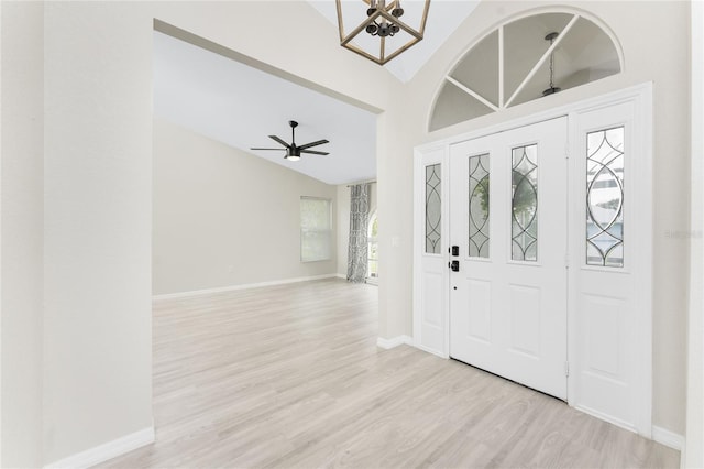 entrance foyer with ceiling fan with notable chandelier, light hardwood / wood-style floors, and lofted ceiling