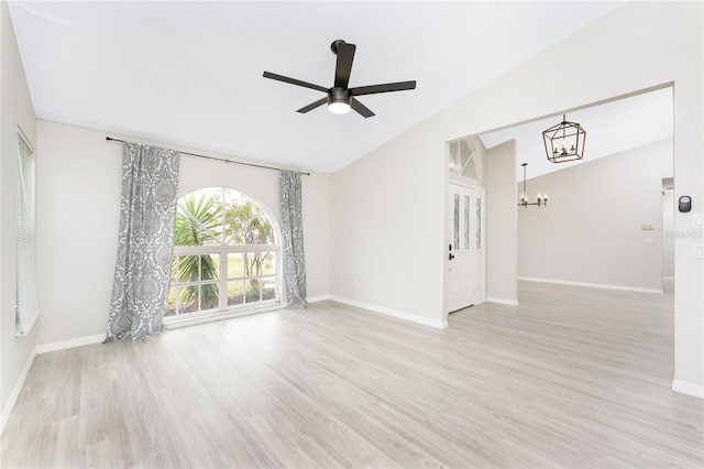 empty room with ceiling fan with notable chandelier, lofted ceiling, and light hardwood / wood-style flooring