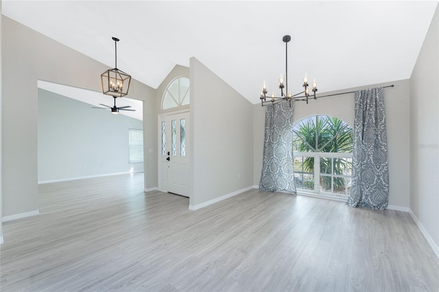 unfurnished room with ceiling fan with notable chandelier, light hardwood / wood-style floors, and plenty of natural light