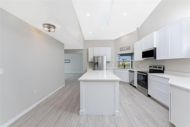 kitchen with white cabinets, sink, light wood-type flooring, appliances with stainless steel finishes, and a kitchen island