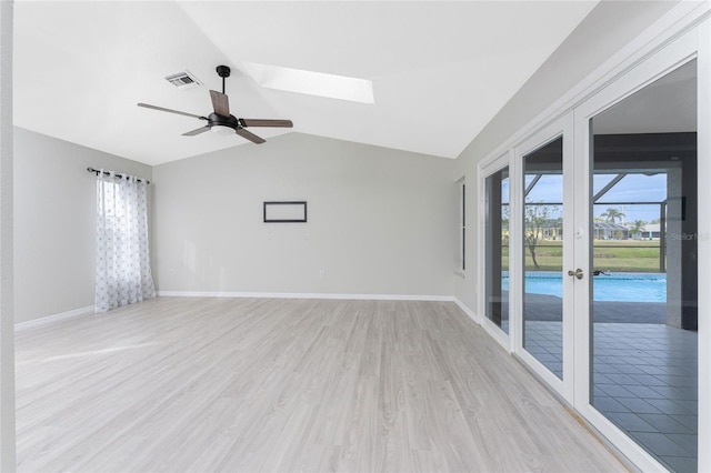 empty room featuring french doors, light hardwood / wood-style floors, lofted ceiling with skylight, and ceiling fan