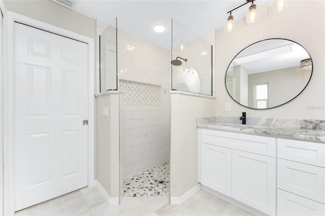 bathroom with a tile shower and vanity